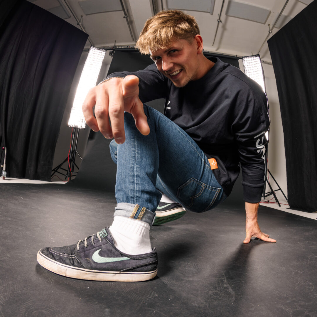 Teammitglied springt vor der Studiowand in die Luft